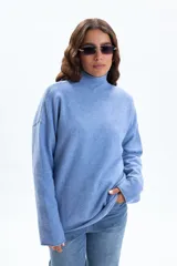 Polera de punto en color celeste, de corte holgado, cuello alto y manga larga con terminaciones simples.