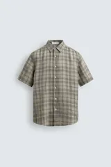 Camisa de lino color beige de corte relajado, con cuello solapa, manga corta y cierre frontal con botones.