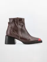 Bota de cuero color marrón con puntera roja, caña media, taco cuadrado y punta cuadrada. Cierre lateral con tirador rojo.