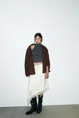 Chaqueta tipo blazer oversize de piel de ante color marrón oscuro, con cuello solapa de muescas, manga larga y bolsillos delanteros con solapa. Cierre frontal con botones.