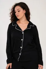 Pijama de dos piezas color negro con ribetes blancos, compuesto por una camisa de manga larga con botones y cuello tipo solapa, y un pantalón largo con cintura elástica.