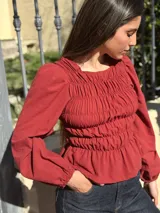 Blusa bordó con diseño fruncido mediante elásticos en el cuerpo y mangas largas abullonadas con puños elásticos.