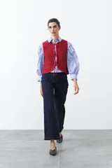 Chaleco de punto con efecto jaspeado en color azul, con diseño sin mangas, escote redondeado y cierre frontal mediante lazos ajustables.