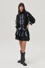 Falda corta de color negro con diseño de doble volado y delicados bordados en tonos celestes que aportan movimiento y estilo.