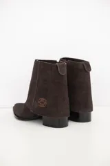 Bota de cuero color chocolate con diseño versátil que incluye una polaina desmontable. Presenta punta fina, taco cuadrado y un detalle bordado en la parte superior de la caña.