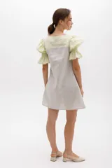 Vestido corto a rayas verticales color gris y blanco, con cuello redondo y mangas cortas abullonadas color amarillo pálido con detalle de elástico en el puño.