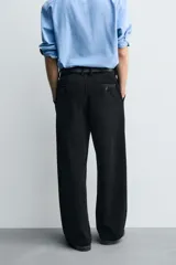 Pantalón de corte wide fit confeccionado en pana de algodón color marrón oscuro. Presenta bolsillos frontales, bolsillos traseros de vivo con botón y cierre frontal con cremallera y botón.
