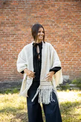 Ruana tejida en crochet de lana merino color crudo, con diseño abierto y flecos decorativos en el ruedo.