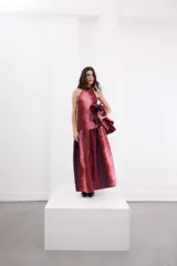Vestido largo de corte holgado con estampado degradé en tonos rojizos y bordó. Presenta escote halter con cuello alto, espalda descubierta con cierre de botones y un maxi volado en la cadera que aporta volumen a la falda.
