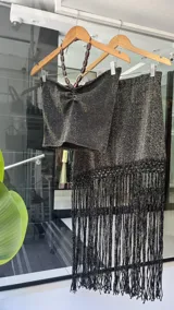 Falda tejida de corte midi color negro con hilo lurex dorado, con detalle de tejido a crochet y flecos largos en el ruedo.