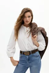 Camisa de algodón color blanco con cuello mao, mangas largas abullonadas con puños elásticos y detalle de volados en la parte frontal. Cuenta con cierre de botones de nácar.