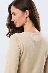 Buzo tejido de algodón color beige, de manga larga, con cuello redondo y delicados motivos bordados distribuidos en la prenda.