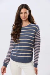Buzo tejido de algodón con diseño a rayas horizontales, cuello redondo y mangas largas. El cuerpo presenta rayas en tonos azul y beige, mientras que las mangas combinan rayas en tonos azul y rosado.