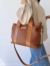 Bolso tipo tote de cuero color marrón con doble asa corta y correa larga extraíble.