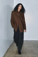 Blazer marrón de la colección Zara Woman, confeccionada en hilatura con 38% lana. Presenta cuello subido, manga larga con abertura y botones, bolsillos con solapa en el delantero y forro interior. Cierre frontal con un botón.