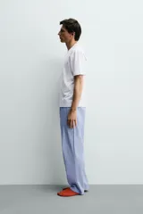 Set de pijama para hombre compuesto por una remera blanca de cuello redondo y mangas cortas, y un pantalón celeste a rayas verticales con cintura elástica y bolsillos laterales.