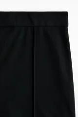 Pantalón en punto pesado de tiro alto, color negro, con elástico oculto en la cintura, cierre y pretina prolongada con corchete oculto. Piernas bootcut con raya cosida.