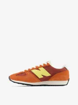 Championes urbanos New Balance modelo U471, con diseño inspirado en el running de los años 70. Presenta una combinación de colores naranja y bordó con el logo lateral en amarillo. Confeccionados con paneles de ante y material sintético, cuentan con entresuela de EVA y suela de goma con diseño de espiga.