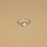 Anillo de plata 925 con banda lisa y un cabezal redondo con una piedra plana de nácar blanca.