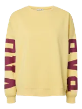 Buzo oversize de color amarillo con cuello redondo y mangas largas, con estampado de letras en color bordó en las mangas.
