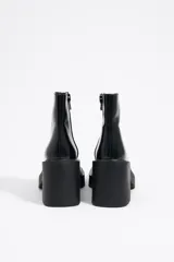 Botín de cuero negro con puntera cuadrada, cierre lateral con cremallera y tacón geométrico.