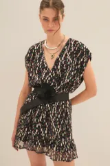 Vestido corto con estampado floral multicolor sobre fondo negro, con hilos metalizados dorados. Presenta escote en V, mangas cortas tipo mariposa y un volante en el ruedo. Se complementa con un cinturón ancho negro con flor decorativa.