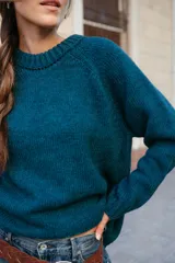 Buzo de lana color rosado, con cuello redondo, mangas largas y diseño holgado.