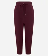 Pantalón de crepé rojo, modelo estilo pijama, de corte fluido, con cintura elástica y lazo de ajuste con terminales metálicas. Cuenta con bolsillos laterales y cierre frontal con cremallera y botón.