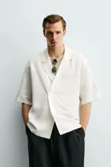 Camisa tipo kimono de corte relaxed fit, color celeste, confeccionada en tejido fluido de viscosa y lino. Presenta cuello con solapas de muesca, manga corta y cierre frontal cruzado con doble botonadura.