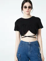 Top corto negro de manga corta con escote redondo. Presenta un diseño fruncido en el busto con un corte central que deja ver parte del abdomen, y tiras finas que se cruzan alrededor de la cintura.