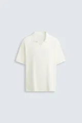 Polo de tejido canalé en color blanco, con cuello solapa y abertura frontal en V, de manga corta y corte regular.