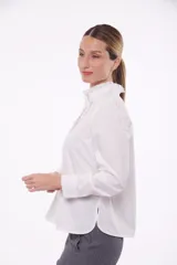 Camisa color blanco con cuello alto con volados y cierre frontal con botones ocultos.