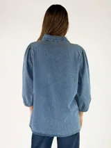 Camisa de denim azul de corte holgado y diseño oversize, con mangas largas abullonadas, puños elásticos y cierre frontal con botones.