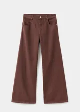 Pantalón de jean estilo wide leg color marrón chocolate, con tiro medio, cinco bolsillos, cierre frontal con cremallera y botón, y detalle de costuras en la cadera.