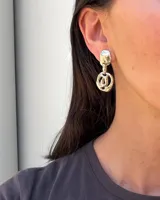 Aros colgantes dorados de diseño orgánico y acabado texturado, compuestos por un botón superior y un eslabón inferior perforado.