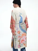 Kimono largo de rayón con diseño artístico estampado que combina motivos florales y figuras de aves. Presenta mangas amplias con detalles en contraste y corte abierto frontal.