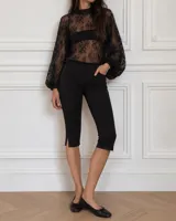 Pantalón capri negro de corte entallado, tiro medio, con bolsillos delanteros y pequeños tajos laterales en los bajos.