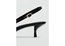 Zapato de tacón tipo slingback en color negro, con diseño destalonado, puntera fina y un detalle de lazo en la parte delantera. Cuenta con tira ajustable en el talón con hebilla metálica dorada y taco fino de altura baja.