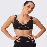 Bra deportivo Fabletics modelo PureLuxe Longline, color negro con ribetes en contraste blancos y logo estampado en el centro.