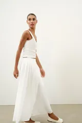 Top de punto canalé en color beige, con escote en pico adornado con una delicada aplicación de encaje blanco y tirantes anchos.