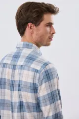 Camisa de lino de manga larga con diseño a cuadros en tonos celeste, blanco y tostado, cuello camisero y cierre frontal con botones.