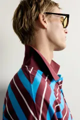 Polo de manga larga con diseño de rayas horizontales en tonos bordó, celeste y blanco, de corte relaxed fit, con cuello tipo polo y cierre frontal de botones.