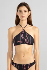 Top de bikini estilo halter confeccionado en tejido reciclado, color negro con estampado de cadenas rosas y detalle de flor en el cuello.