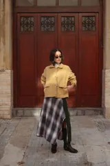 Chaqueta de lana afieltrada color amarillo, con cuello camisero, cierre frontal con broches a presión y bolsillos delanteros. Presenta un diseño de corte holgado con una apertura en la espalda que aporta movimiento.