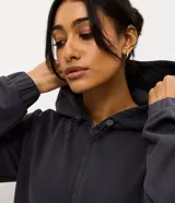 Campera deportiva Get Over de corte regular, confeccionada en tejido texturizado color gris oscuro. Presenta cierre frontal con zíper, capucha con cordones ajustables y mangas largas con puños elásticos.