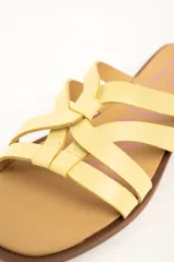 Sandalias planas de cuero color amarillo, con múltiples tiras finas entrelazadas en el empeine, suela baja y plantilla marrón.