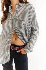 Camisa de corte oversize color bordó, con cuello clásico, cierre frontal de botones y detalle de trenzado horizontal en la parte superior delantera. Posee mangas largas con puños abotonados.