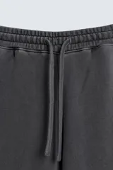 Pantalón jogger de corte wide fit confeccionado en tejido de algodón con interior de rizo. Presenta cintura elástica ajustable con cordón, bandas laterales decorativas, bolsillos laterales y un bolsillo trasero de plastrón. El acabado presenta un efecto lavado que le otorga una apariencia única.