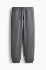 Pantalón deportivo de felpa con mezcla de algodón y corte relajado, color gris oscuro, con cintura elástica ajustable mediante cordón, bolsillos laterales y puños acanalados.