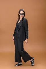 Pantalón sastrero de corte ancho y tiro alto, con diseño de líneas limpias, bolsillos laterales y cierre frontal con botón. Presenta una caída fluida y estructura amplia.